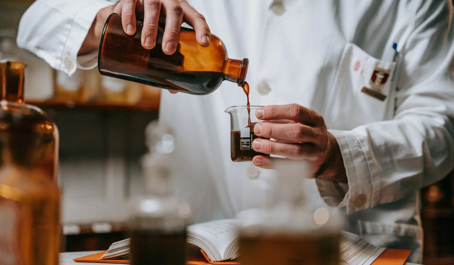 Apotheker in weißem Mantel mischt Substanzen